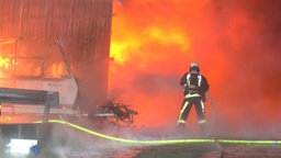 Feuerwehrmann vor einer brennenden Lagerhalle