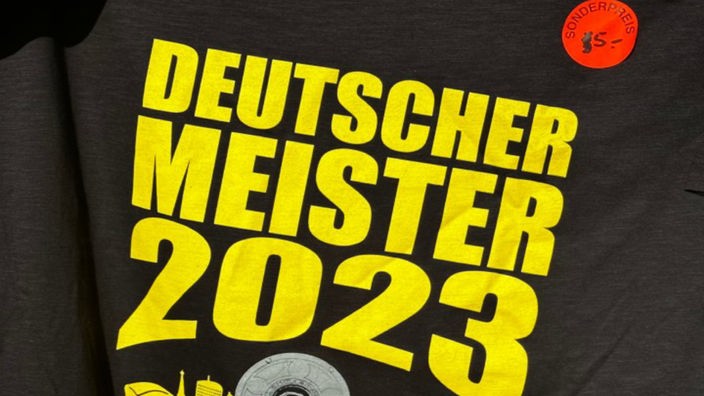 Shirt mit dem Aufdruck "Deutscher Meister 2023" mit Sonderpreis-Aufkleber