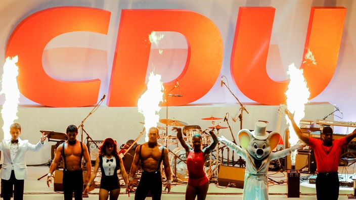 Eine Tanzgruppe steht vor einem CDU-Logo auf der Bühne