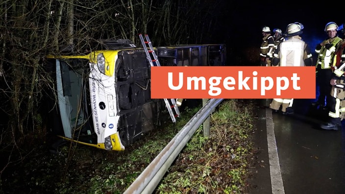 Ein Linienbus liegt auf der Seite neben einer Straße