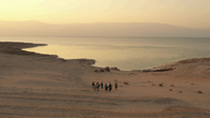 Die Reisegruppe wandert bei Sonnenaufgang zu einem Strand am Toten Meer.