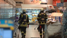 Zwei Feuerwehr Männer laufen durch einen Discounter