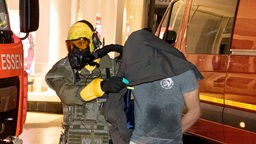 Ein Mann wird von Beamten des Spezialeinsatzkommandos (SEK) mit Schutzmaske in Gewahrsam genommen.