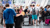 Reisende warten an einem Check-In-Schalter in der Abflughalle des Flughafens