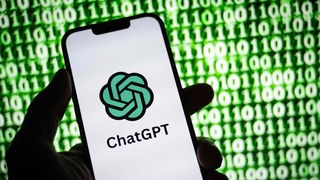 Das Icon von ChatGPT auf einem Smartphone-Display vor Binärcodes.