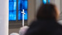 13.02.2022, Bayern, Aschaffenburg: Ein christliches Kreuz wird während einer Solidaritätsaktion vom hereinfallenden Tageslicht angeleuchtet