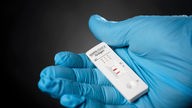 Schutzhandschuh hält Corona Virus Test von erkrankter Person
