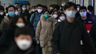 Peking: Pendler mit Schutzmasken gehen während des morgendlichen Berufsverkehrs auf dem Weg zur Arbeit in Peking durch einen Gang zwischen zwei U-Bahn-Stationen