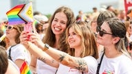 Drei Teilnehmerinnen machen Selfies beim CSD in Köln.