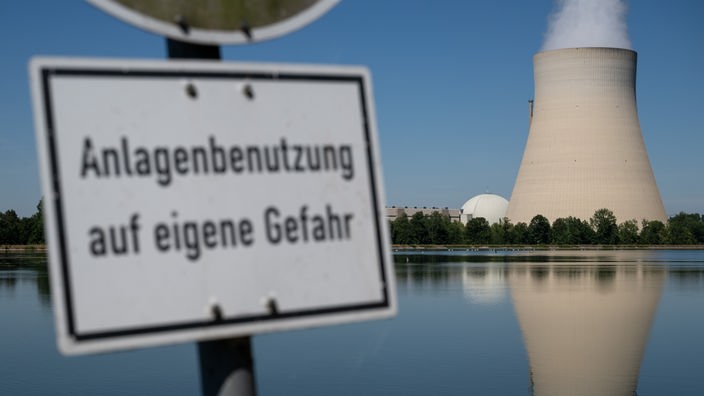 Atomkraftwerk, davor Schild mit der Aufschrift "Anlagenutzung auf eigene Gefahr"