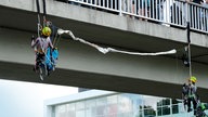 Zwei Kinder seilen sich bei der Demo in Aachen von einer Brücke ab