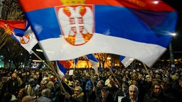 Demonstranten schwenken eine Flagge vor dem Rathaus in Belgrad