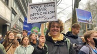 Demonstrant Finn Eriksen aus Köln mit einem Schild "Noch können wir entscheiden was wird ... was wird"