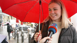 Frau wird mit einem Mikrofon bei einer Straßenumfrage interviewt 