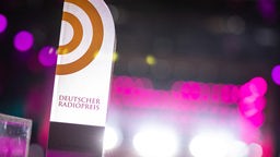Der Award für den Deutschen Radiopreis vor verschwommenen magenta Bühnenlichtern