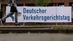 Ein Mann geht an einem Plakat mit der Aufschrift «Deutscher Verkehrsgerichtstag» vorbei.