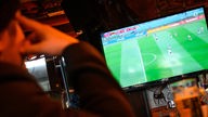 Ein Mann schaut Uhr auf einem Fernseher das erste Spiel der Deutschen Nationalmannschaft gegen Japan