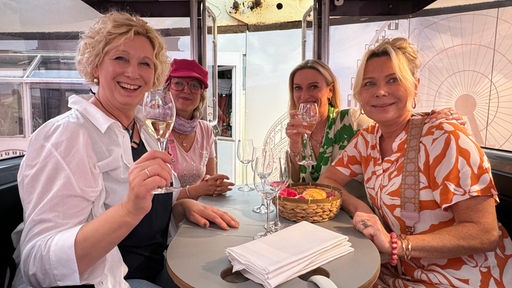 Vier Damen trinken in der Riesenradkabiene Wein.