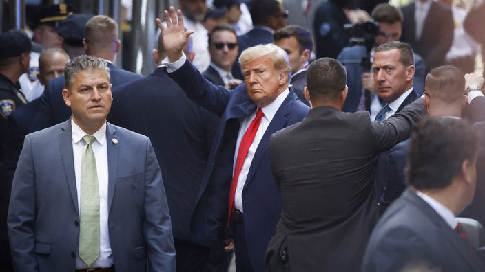 Der ehemalige US-Präsident Donald Trump winkt, als er vor dem Strafgericht in Manhattan zu seiner Anklageverlesung erscheint.