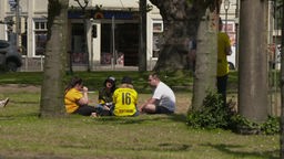 Menschen in BVB Trikots sitzen am Borsigplatz in Dortmund