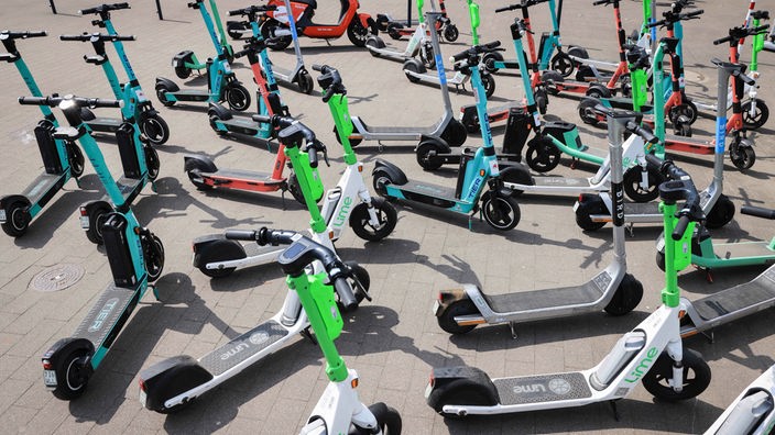 Symbolbild: Mehrere E-Scooter verschiedener Anbieter stehen auf einem Platz