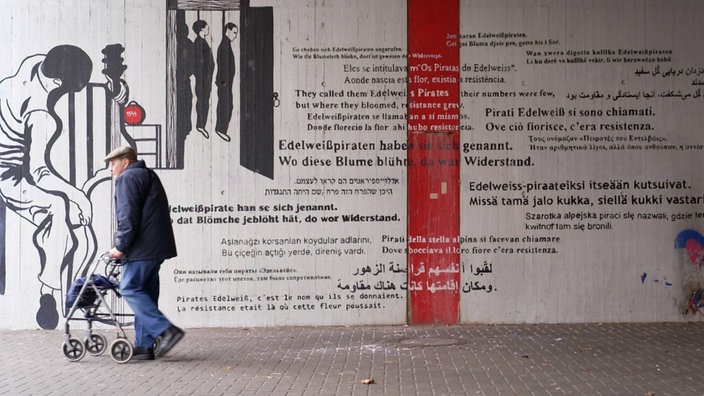 Mann mit Rollator vor Wandkunstwerk am Bahnhof