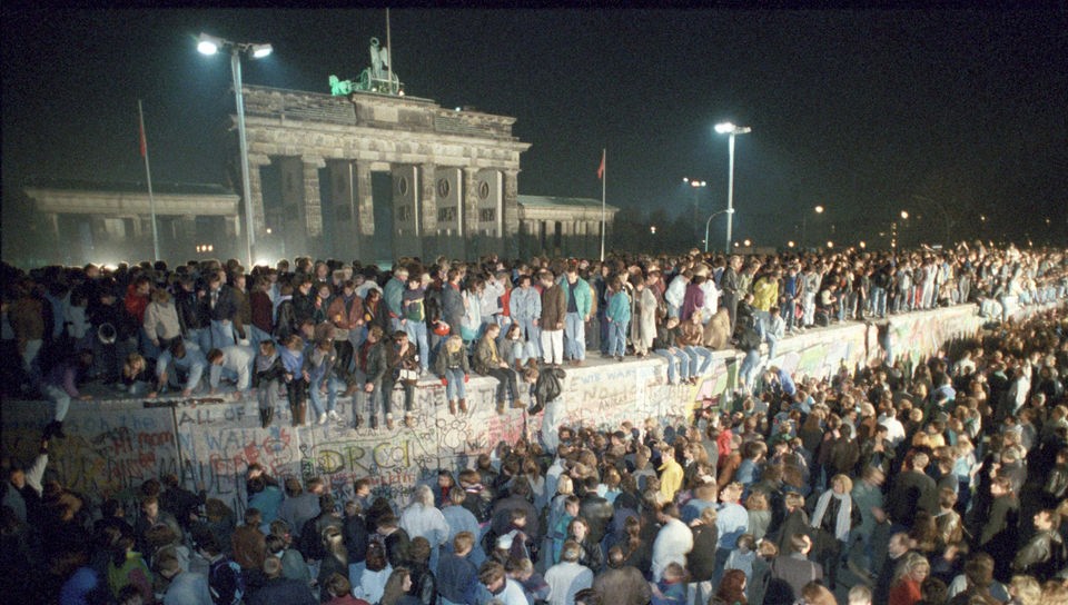 Viele Menschen stehen nachts auf der Berliner Mauer.