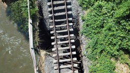 Blick von oben auf die Schienen einer nach einem Unwetter beschädigten Eisenbahnbrücke.