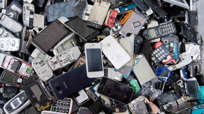Alte Handys und Smartphones liegen in einem Container, ehe sie geschreddert werden