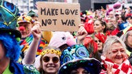 Kostümierte mit Schild "Make Love Not War" bei der Karneval-Sessionseröffnung am Kölner Heumarkt