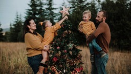 Eine Familie schmückt zusammen einen Weihnachtsbaum