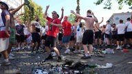 Englische Fußballfans stehen neben leeren Flaschen vor einem zwischen England und Slowenien