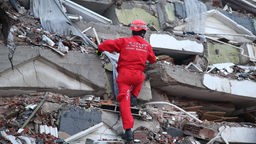 Ein Retter sucht nach Überlebenden auf den Trümmern eines Gebäudes.