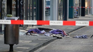 Scherben und Kleidungstücke liegen vor einem Geschäft in der Ehrenstraße in Köln