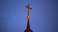 Ein Kreuz steht auf der Kirchturmspitze einer evangelischen Kirche in der Region Hannover.