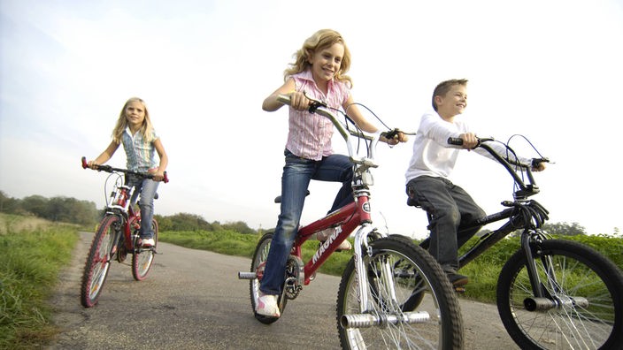 Drei Kinder sind mit den Fahrrädern unterwegs