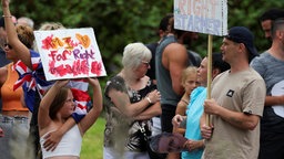 Ein junges Mädchen hält ein rechtes Protestplakat in die Luft