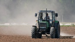 Ein Landwirt eggt am Freitag mit einem Traktor ein Feld bei Trebur