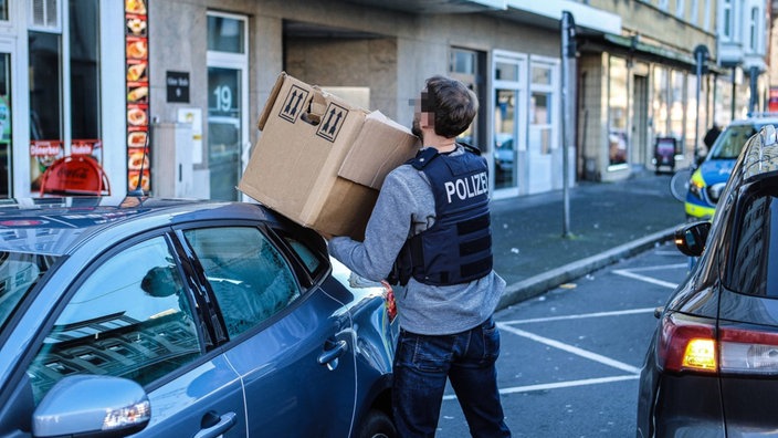 Ein Polizeibeamter trägt einen Karton.