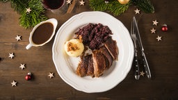 Vogelperspektive auf eine einen Teller mit Weihnachtsgans einem Knoedel und Rotkohl