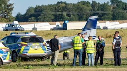 16.07.2022, Würselen: Einsatzkräfte der Polizei stehen neben einem abgestürzten Kleinflugzeug