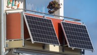Solarmodule für ein sogenanntes Balkonkraftwerk hängen an einem Balkon