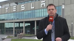 Ein Reporter des RBB steht vor dem Eingang der Tesla-Fabrik