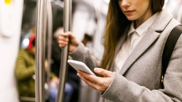 Frau nutzt ihr Smartphone in der Bahn