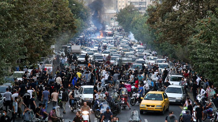 Eine Straße ist voll mit Menschen, Autos und Feuer