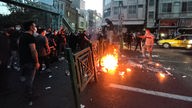 Menschen stehen vor brennenden Barrikaden auf der Straße