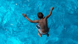 Ein Junge springt im Stadionbad in Köln ins Wasser.