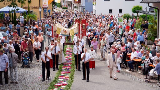 Gläubige gehen während einer Fronleichnams-Prozession in Mühlenbach an einem Blumenteppich entlang