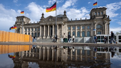 Passanten gehen beim sonnigen Wetter an dem Reichstagsgebäude vorbei