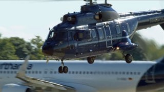 Hubschrauber landet vor Flugzeug